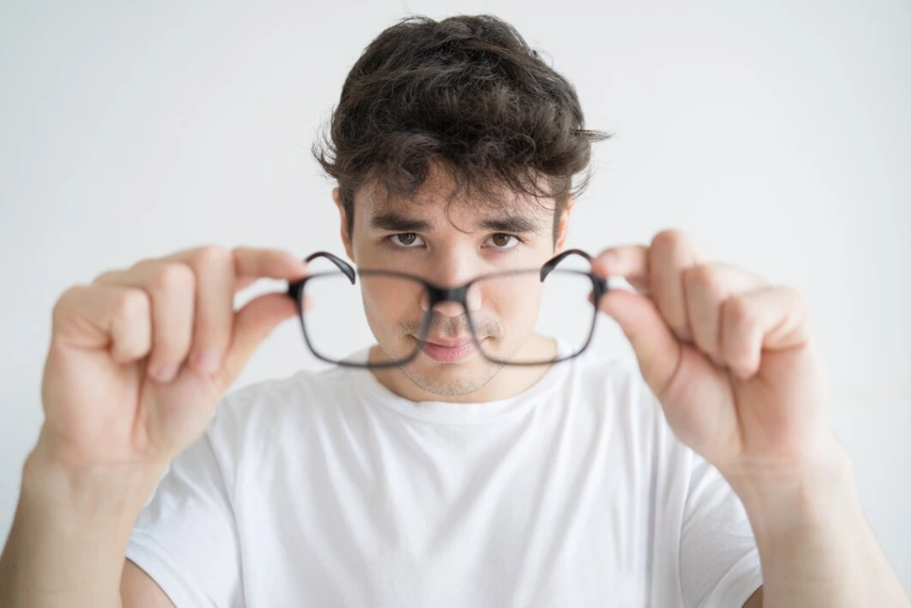 man holding glasses after prk surgery vision correction treatment
